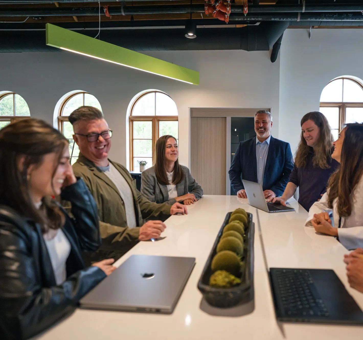 Image of the Nextpoint team chatting and working at a long table.